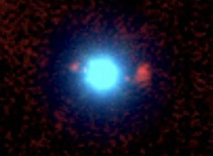 Der erste beobachtete Fall eines starken Gravitationslinseneffekts durch einen Quasar: Auf dieser Aufnahme des Keck-II-Teleskops mit der Kamera NIRC-2 erscheint dieser grell in Blau, umgeben von zwei Bildern der Hintergrundgalaxie – links dicht daneben, rechts diffuser in größerem Abstand – in Rot. [F. Courbin, G. Meylan, S. G. Djorgovski, et al., EPFL/ Caltech/WMKO]